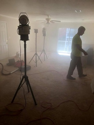 A man in an empty room with smoke coming from the ceiling.